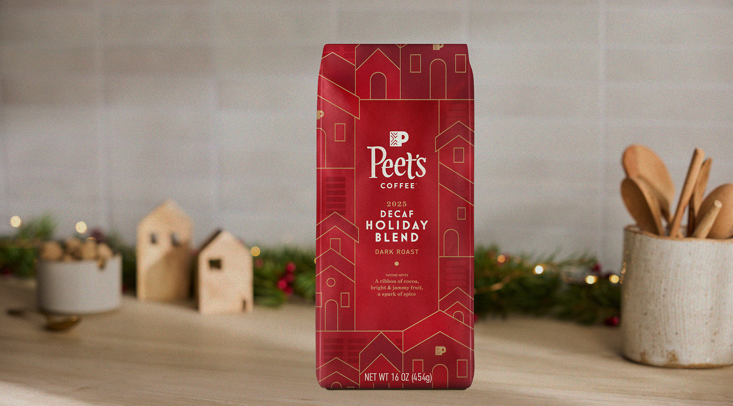 Red Peet's Coffee Decaf Holiday Blend package on a wooden surface with festive decorations.